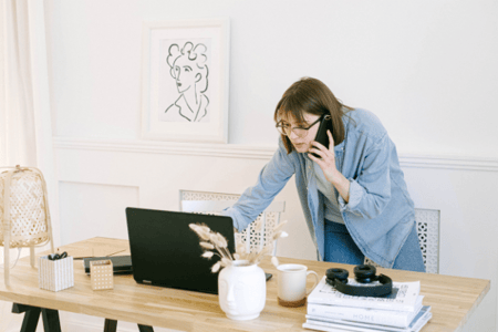 personne au téléphone penché sur son ordinateur 